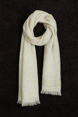 Off-white linen and silk blend basket weave stole with soft fringe edges, draped in a looped style against a dark textured background – handwoven in Nepal.